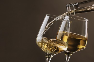 Photo of Pouring tasty aromatic wine in glass on gray background, closeup. Space for text
