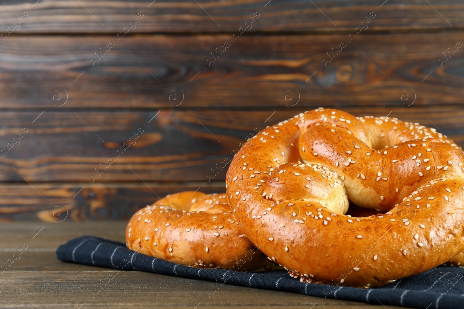 Photo of Tasty freshly baked pretzels on wooden table, closeup. Space for text