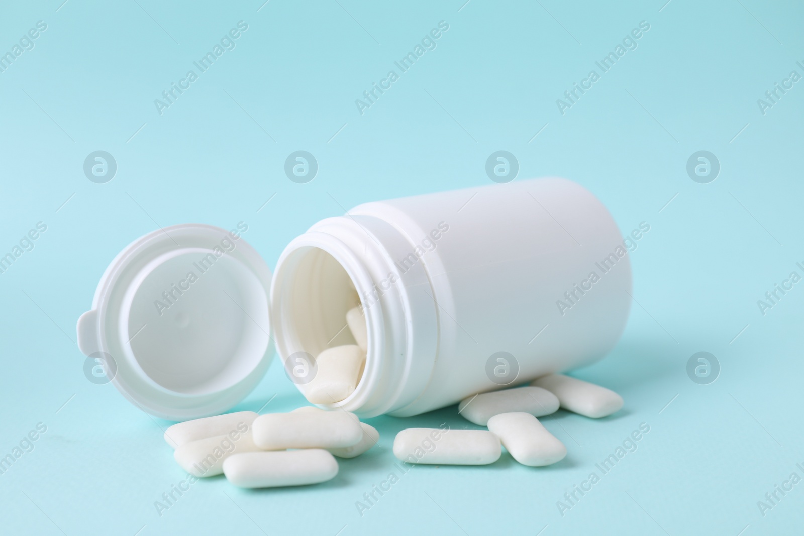 Photo of Jar with chewing gums on light blue background, closeup