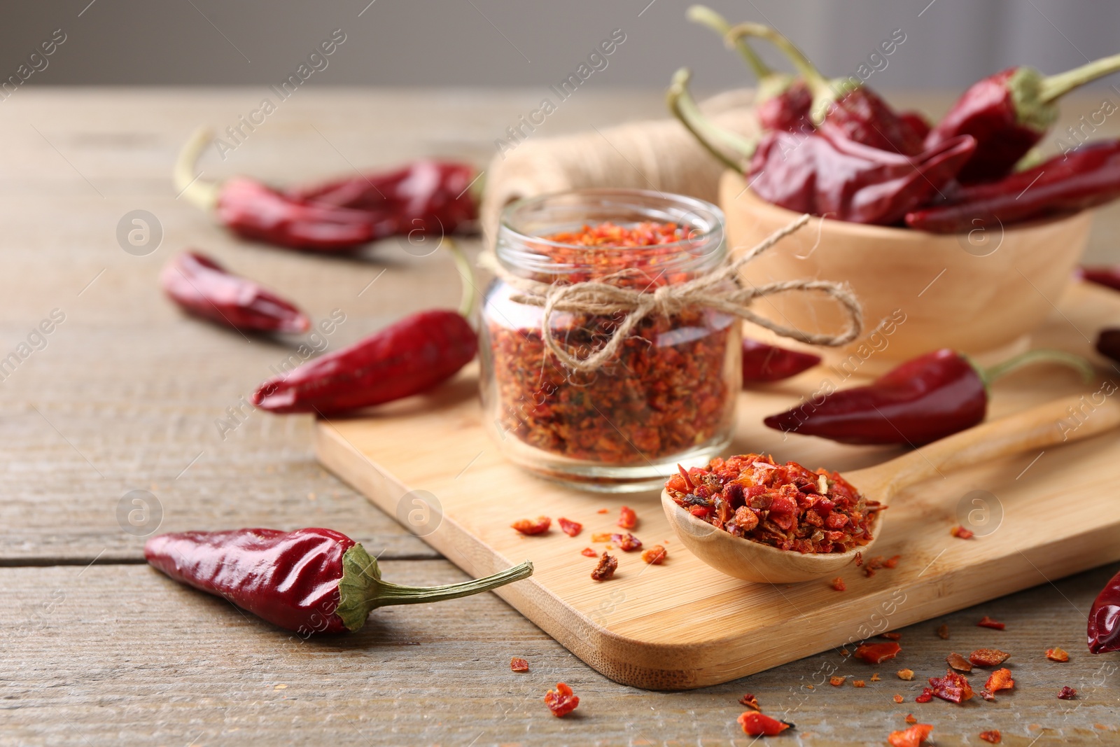 Photo of Chili pepper flakes and pods on wooden table