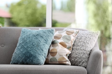 Photo of Different soft pillows on sofa in room. Interior element