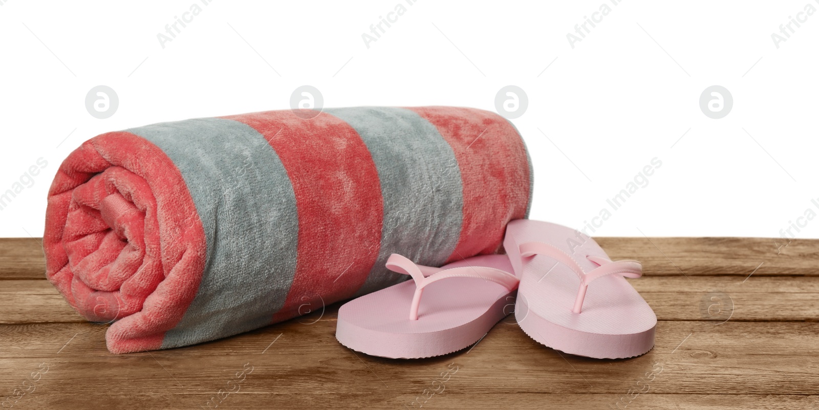 Photo of Beach towel and flip flops on wooden surface against white background