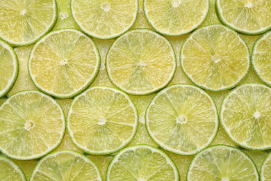 Many fresh juicy lime slices as background, top view