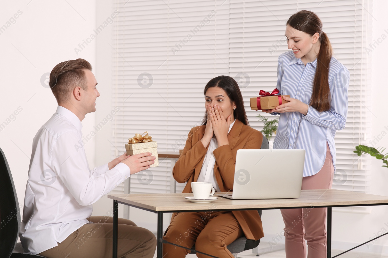 Photo of Colleagues presenting gifts to woman in office