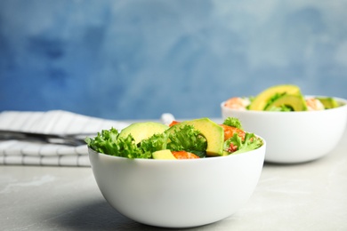 Delicious avocado salad with shrimps in bowl on grey marble table