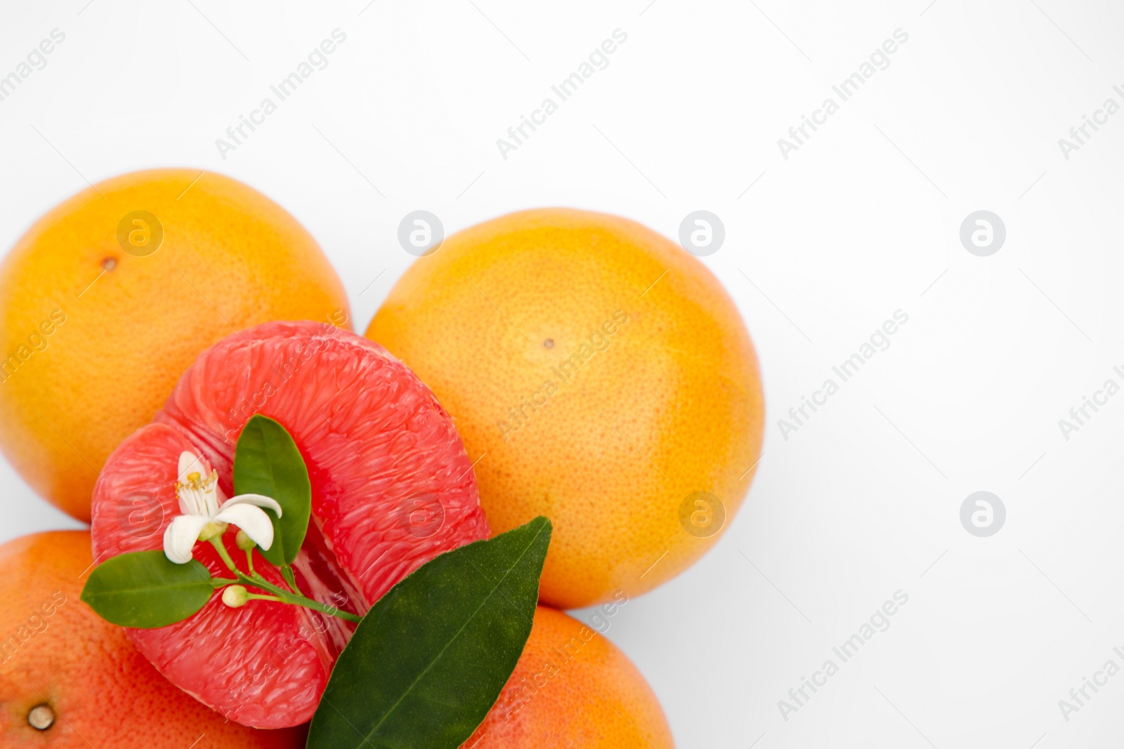 Photo of Fresh grapefruits and green leaves on white background, above view. Space for text