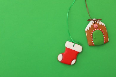 Photo of House and stocking shaped Christmas cookies on green background, flat lay. Space for text