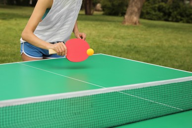 Photo of Woman playing ping pong outdoors on summer day, closeup
