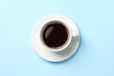 Cup of aromatic coffee on light blue background, top view