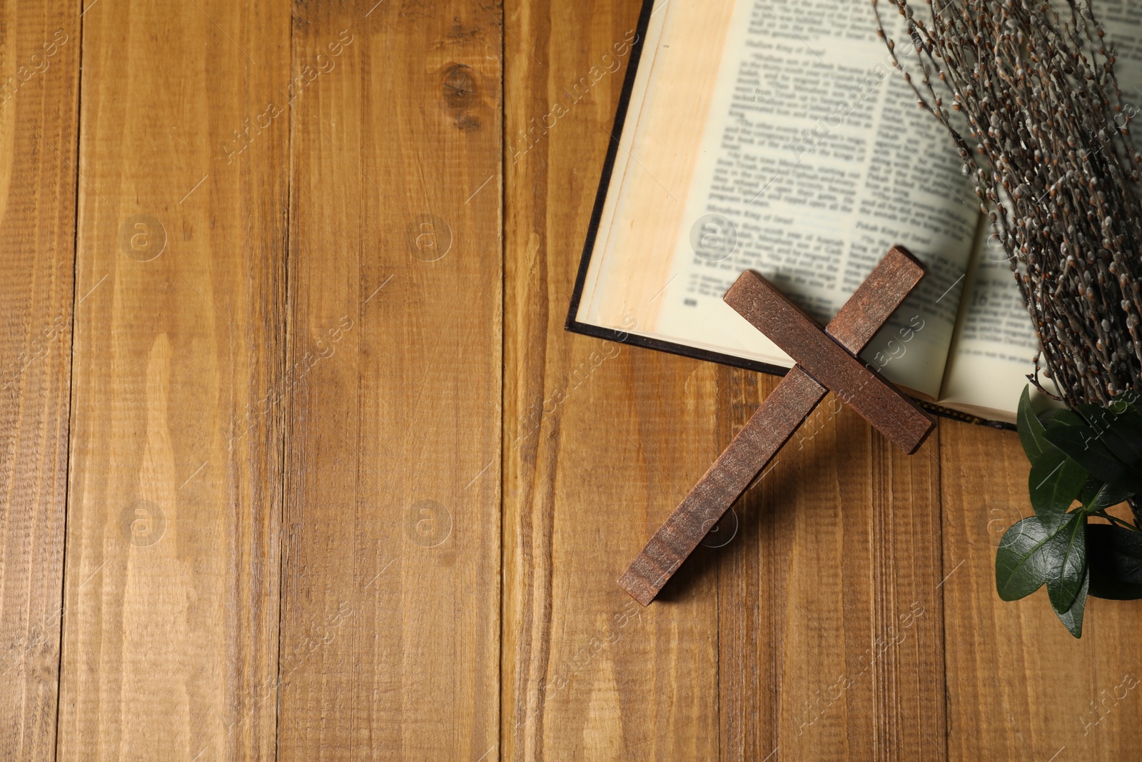 Photo of Cross, Bible and willow branches on wooden table, flat lay. Space for text