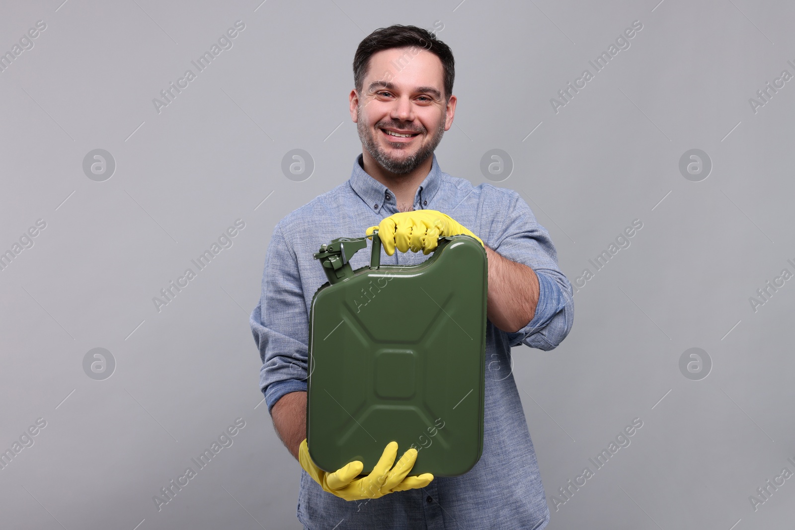 Photo of Man holding khaki metal canister on light grey background