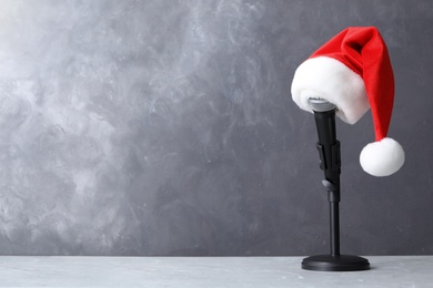 Microphone with Santa hat on table against grey background, space for text. Christmas music