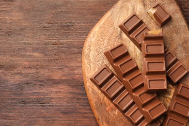 Photo of Tasty chocolate bars on wooden table, top view. Space for text