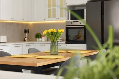 Spring atmosphere. Stylish kitchen interior with comfortable furniture and bouquet of beautiful yellow tulips