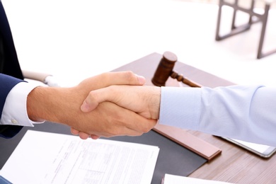 Lawyer handshaking with client over table in office, closeup