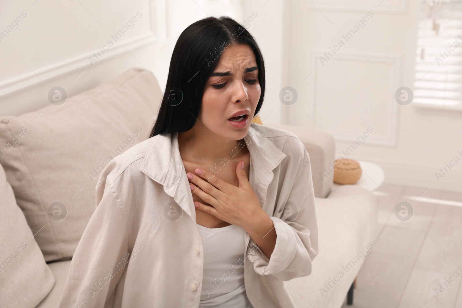 Photo of Young woman suffering from breathing problem on sofa at home