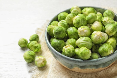 Photo of Bowl of fresh Brussels sprouts and napkin on table. Space for text