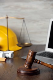 Construction and land law concepts. Judge gavel, scales of justice, protective helmet, drawings with laptop on wooden table