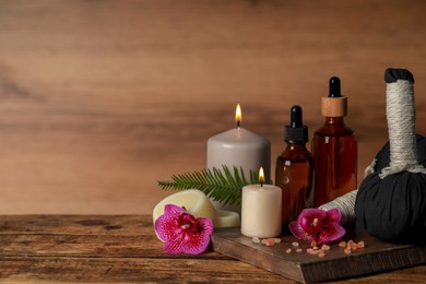 Photo of Beautiful spa composition with different care products and burning candles on wooden table. Space for text