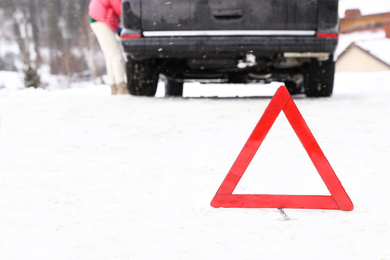 Photo of Emergency stop sign and broken car on snowy road in winter