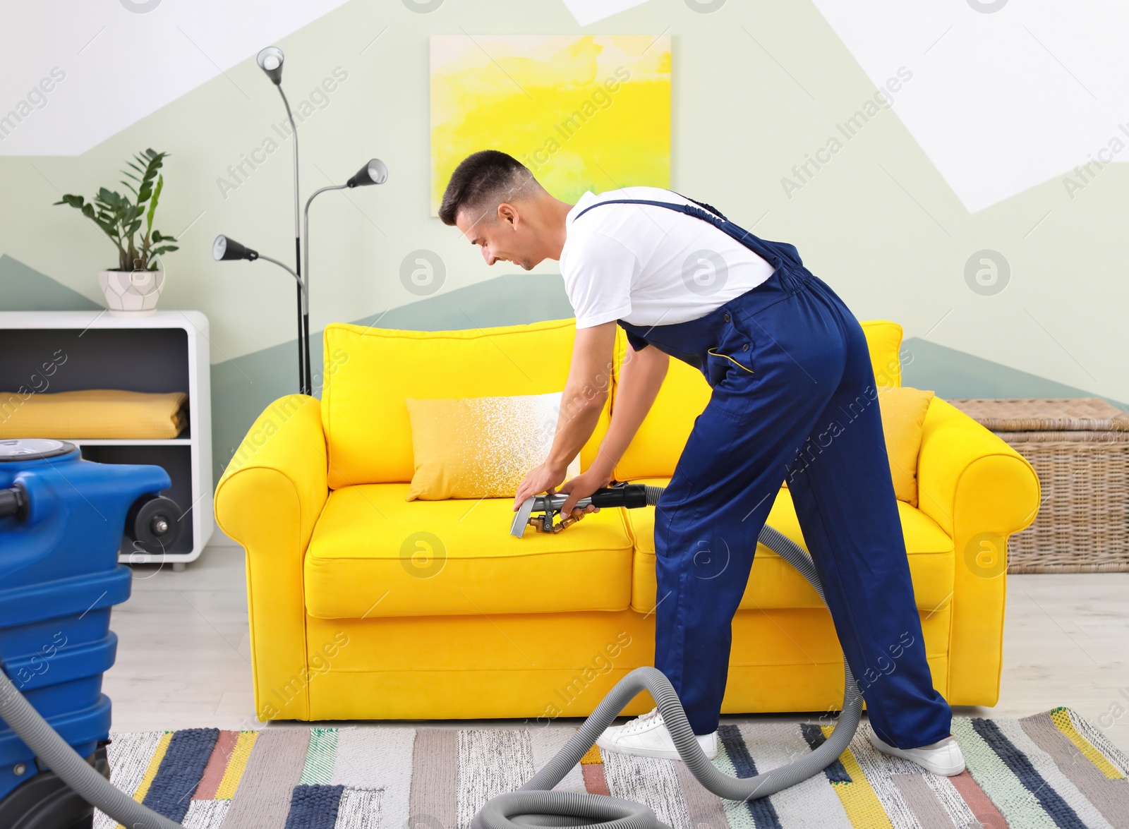 Photo of Dry cleaning worker removing dirt from sofa indoors