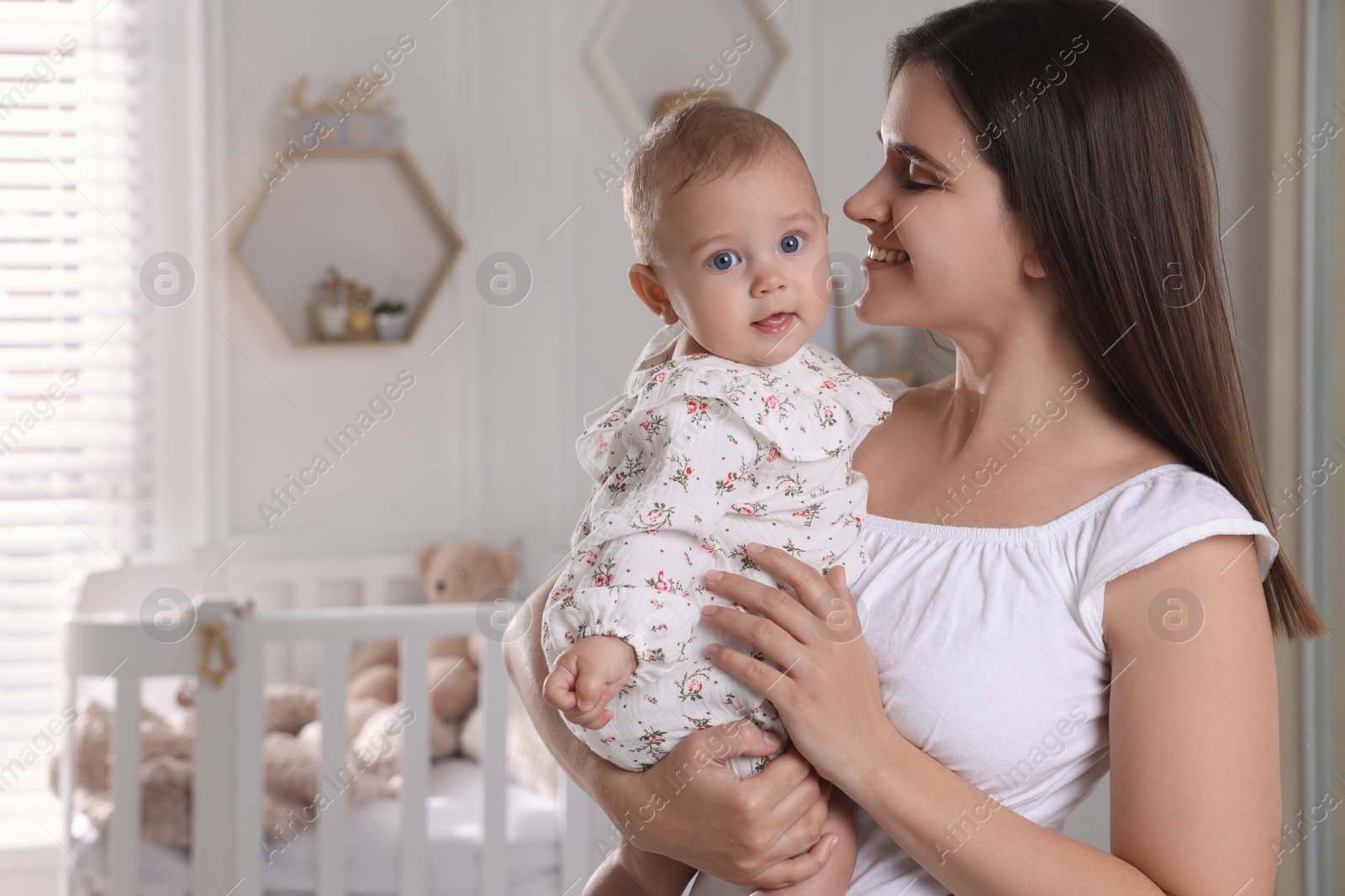 Photo of Happy young mother with her baby daughter in nursery. Space for text