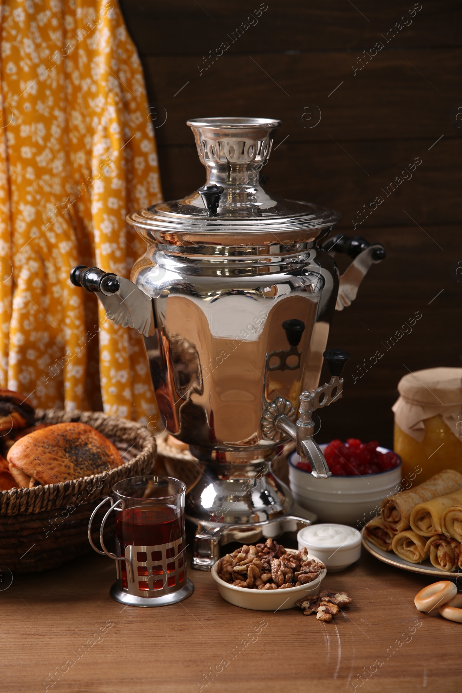 Photo of Traditional Russian samovar and treats on wooden table