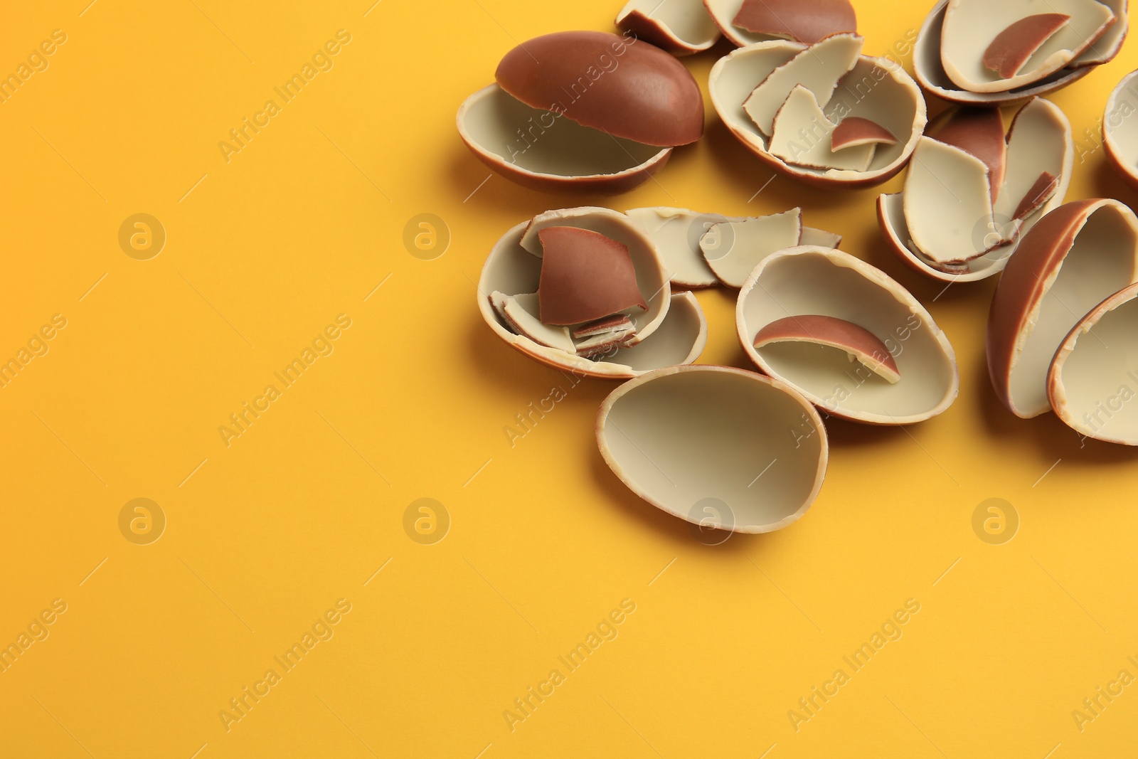 Photo of Sveti Vlas, Bulgaria - July 3, 2023: Broken halves of Kinder Surprise Eggs on yellow background, above view. Space for text