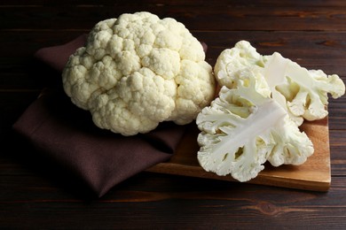 Photo of Board with fresh raw cauliflower on wooden table