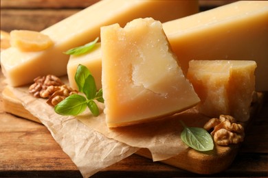 Photo of Delicious parmesan cheese with walnuts and basil on wooden table, closeup