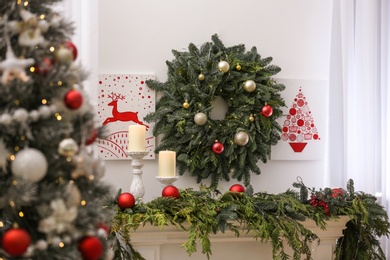 Beautiful Christmas pictures and wreath on wall in decorated room. Interior design