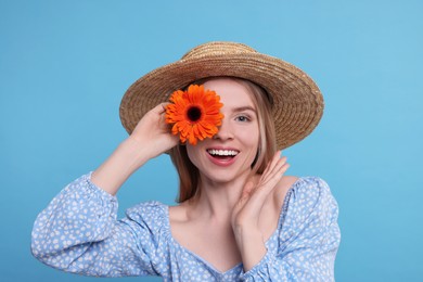 Photo of Beautiful woman with spring flower in hand on light blue background