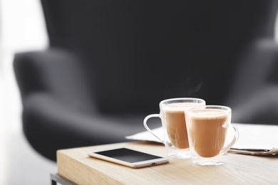 Photo of Cups of coffee and mobile phone on table
