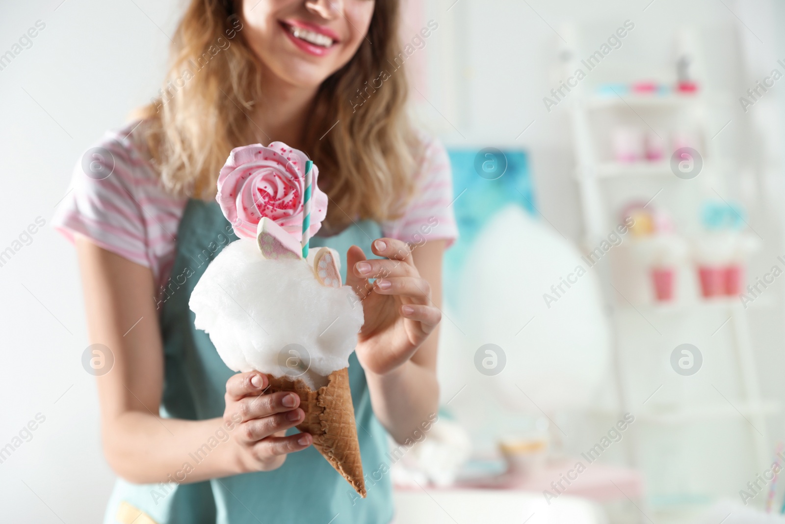 Photo of Young woman with cotton candy dessert indoors, closeup. Space for text