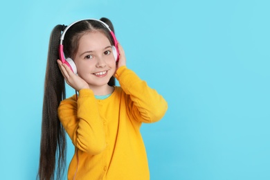Cute girl enjoying music in headphones on color background. Space for text