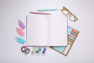 Open planner, stationery and glasses on white background, flat lay