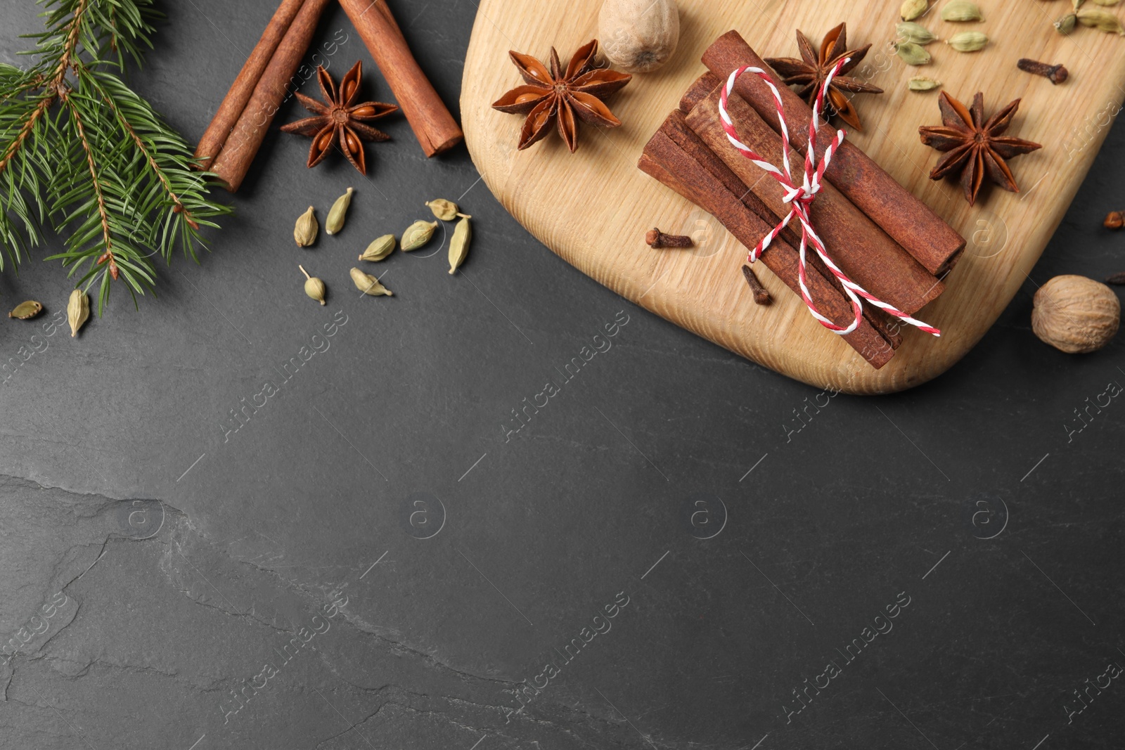 Photo of Different spices, nuts and fir branches on gray table, flat lay. Space for text