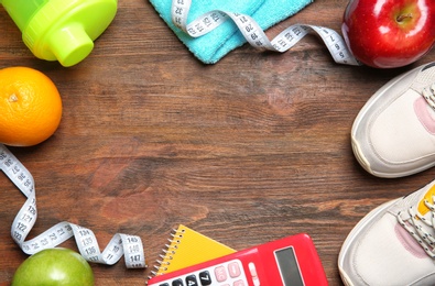 Photo of Flat lay composition with sneakers, healthy food, calculator and space for text on wooden background. Weight loss concept