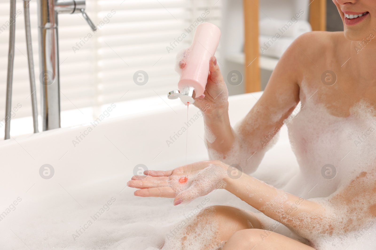 Photo of Woman pouring shower gel onto hand in bath indoors, closeup