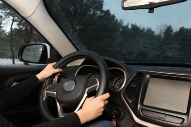 Photo of Young woman driving car along winter forest, closeup