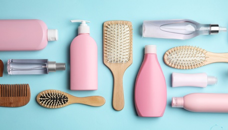 Flat lay composition with brushes and hair care cosmetics on light blue background