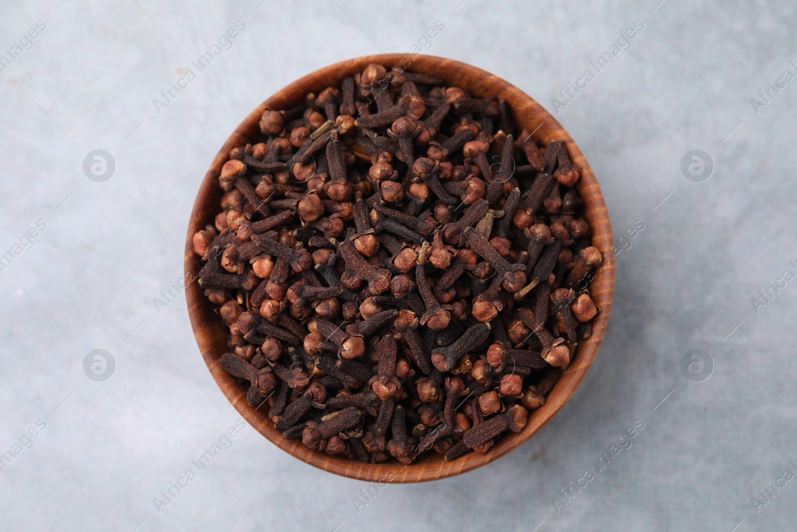 Photo of Aromatic cloves in bowl on gray table, top view