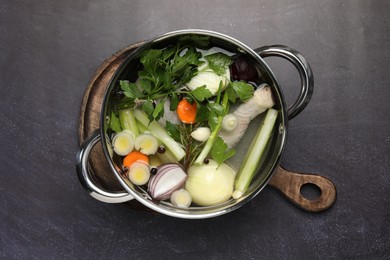 Different ingredients for cooking tasty bouillon in pot on black table, top view