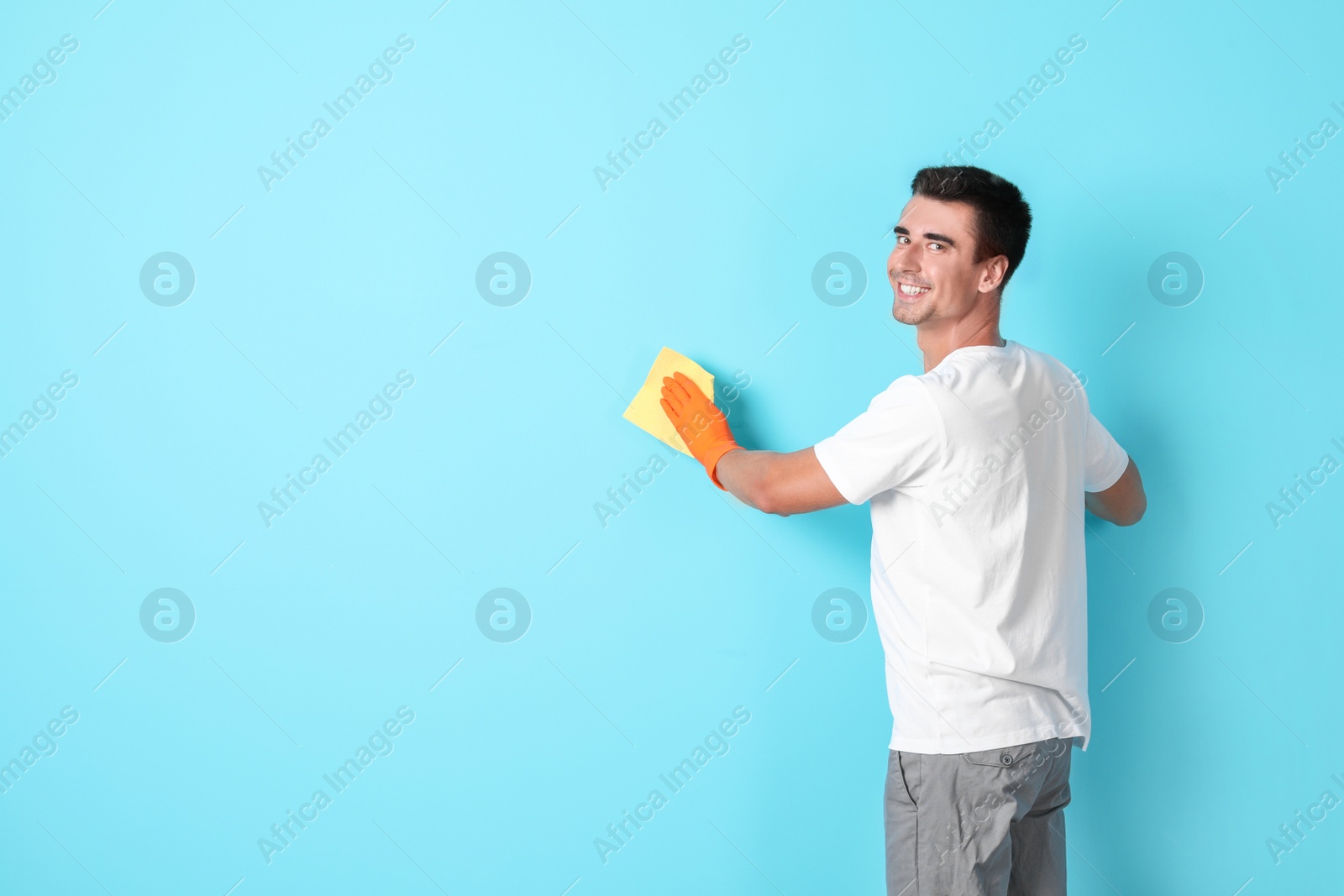 Photo of Man in gloves cleaning color wall with rag