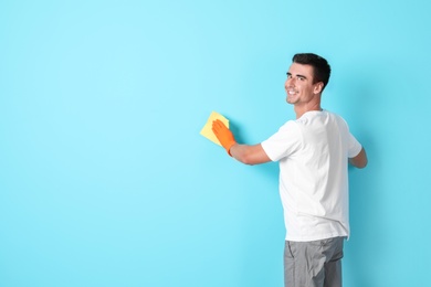 Man in gloves cleaning color wall with rag