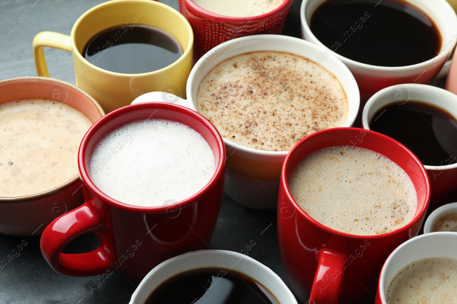 Photo of Many cups of different coffees on grey table, closeup