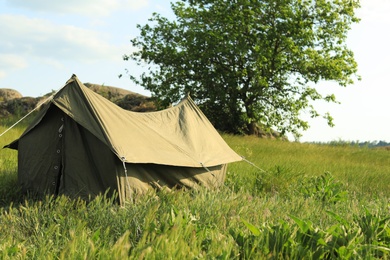 Photo of Camping tent in green field on sunny day. Space for text