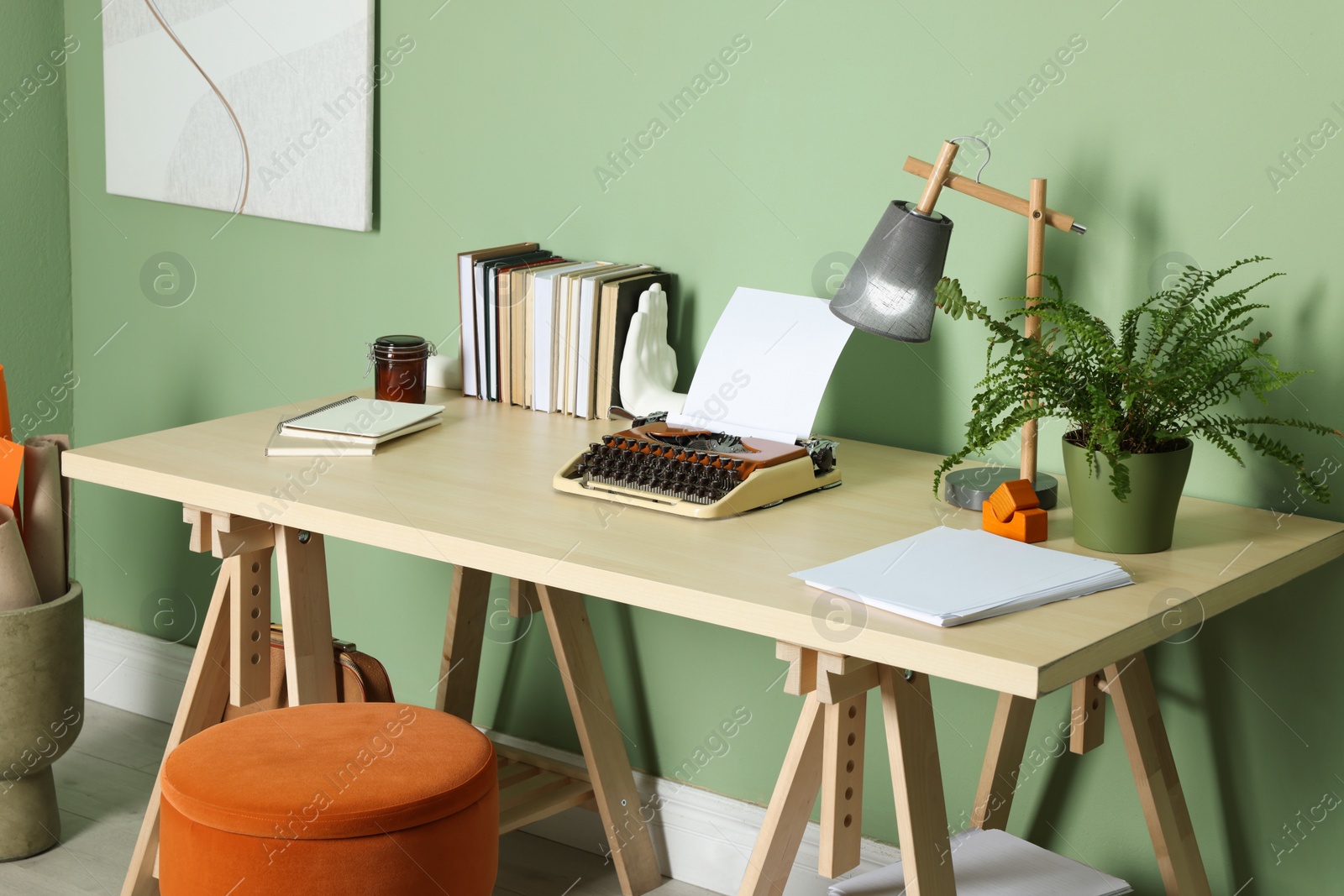 Photo of Writer's workplace with typewriter on wooden desk near pale green wall in room