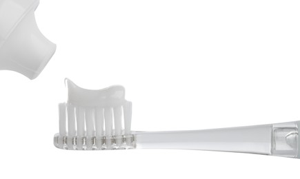 Applying paste on electric toothbrush against white background, closeup