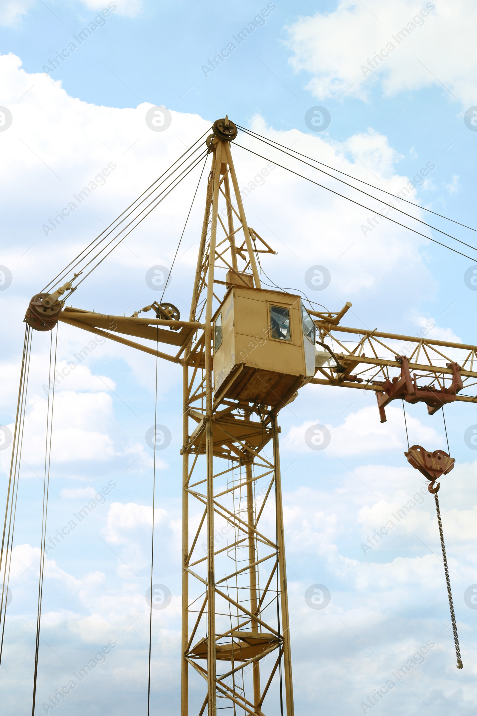 Photo of Tower crane under cloudy sky, low angle view. Construction site